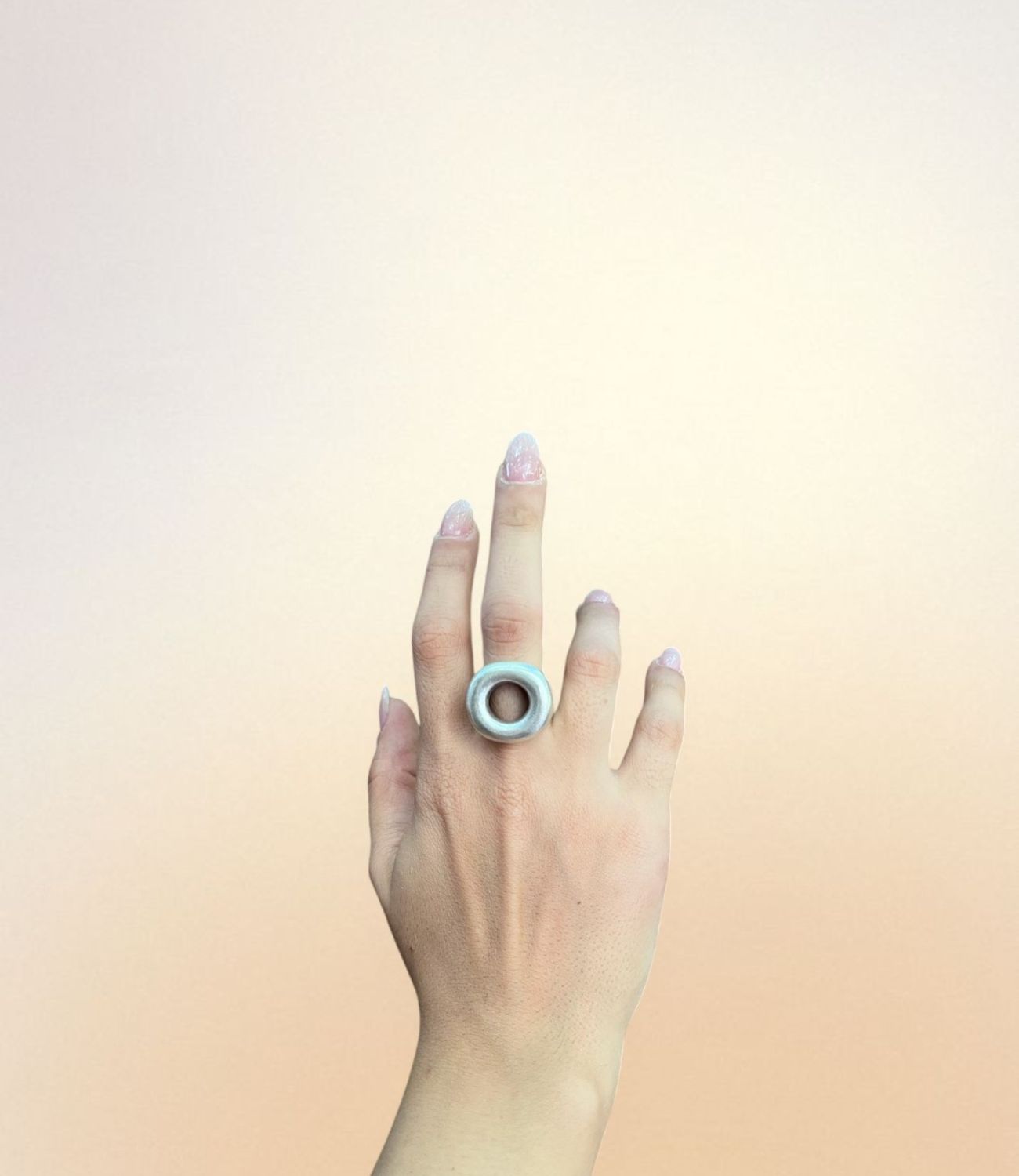 A hand wearing the Halo Ring — a thick, silver-plated ring with a clean circular shape and an open hollow center, creating a bold and modern statement.
