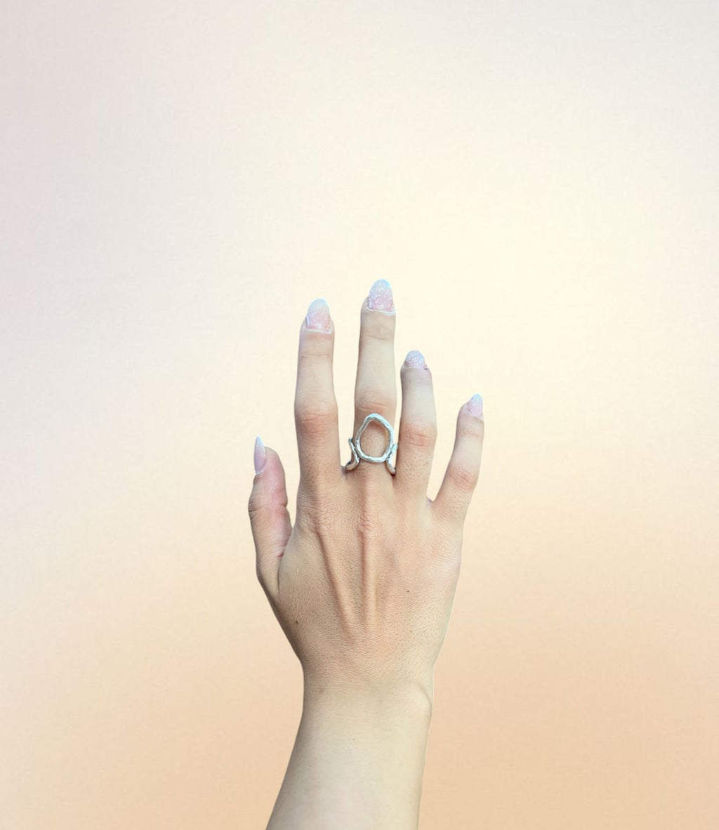 Silver-plated open swirl ring with twin curved arms and organic circular center, worn on hand