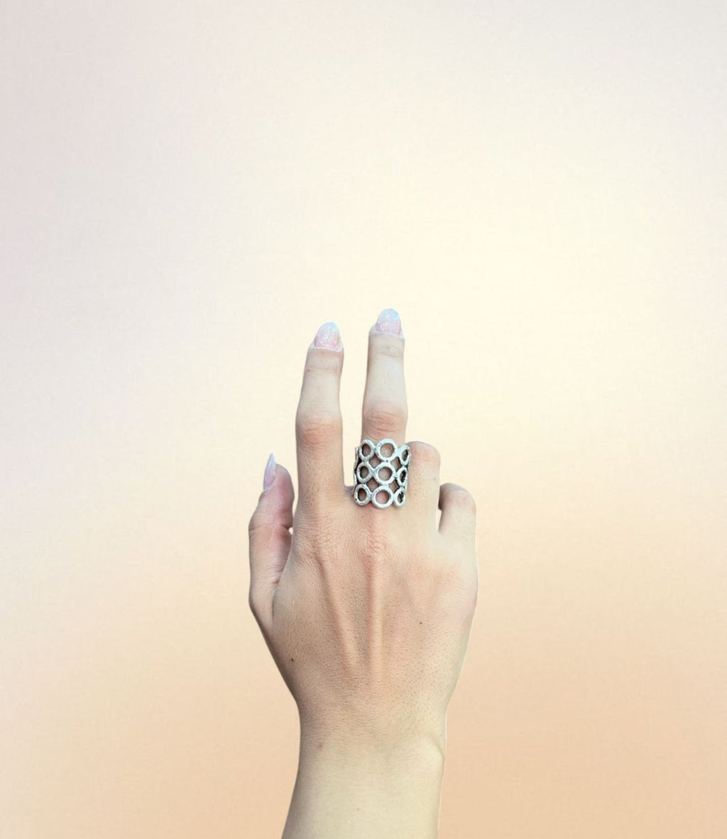 Wide silver ring with honeycomb-style open oval pattern, worn on hand