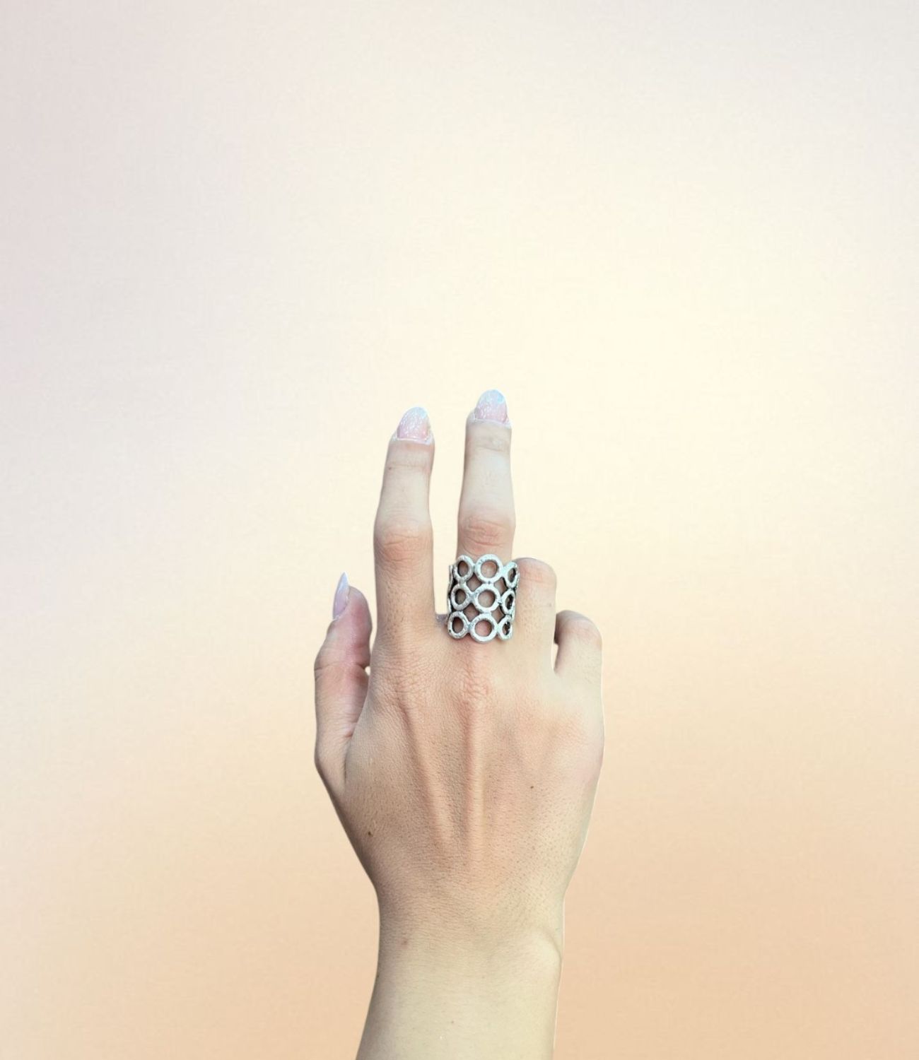 Wide silver ring with honeycomb-style open oval pattern, worn on hand