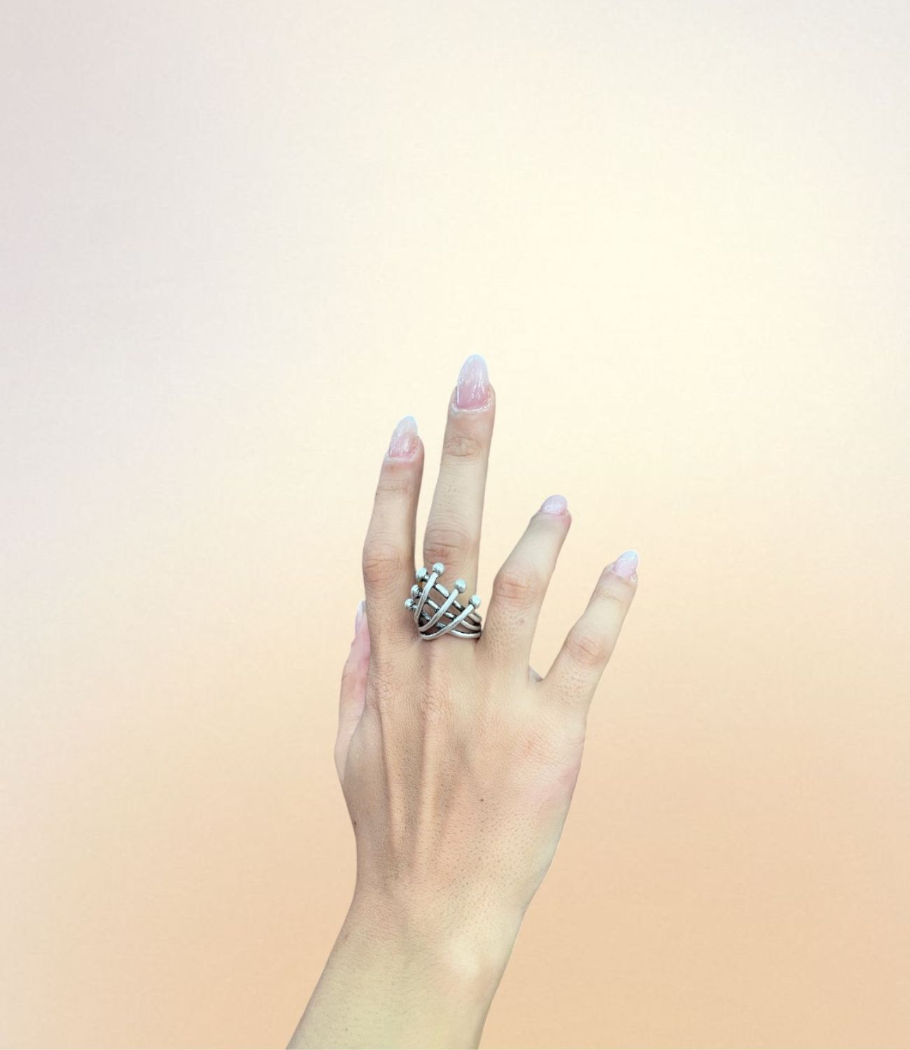 Layered silver ring with spherical tips resembling orbiting planets, worn on hand